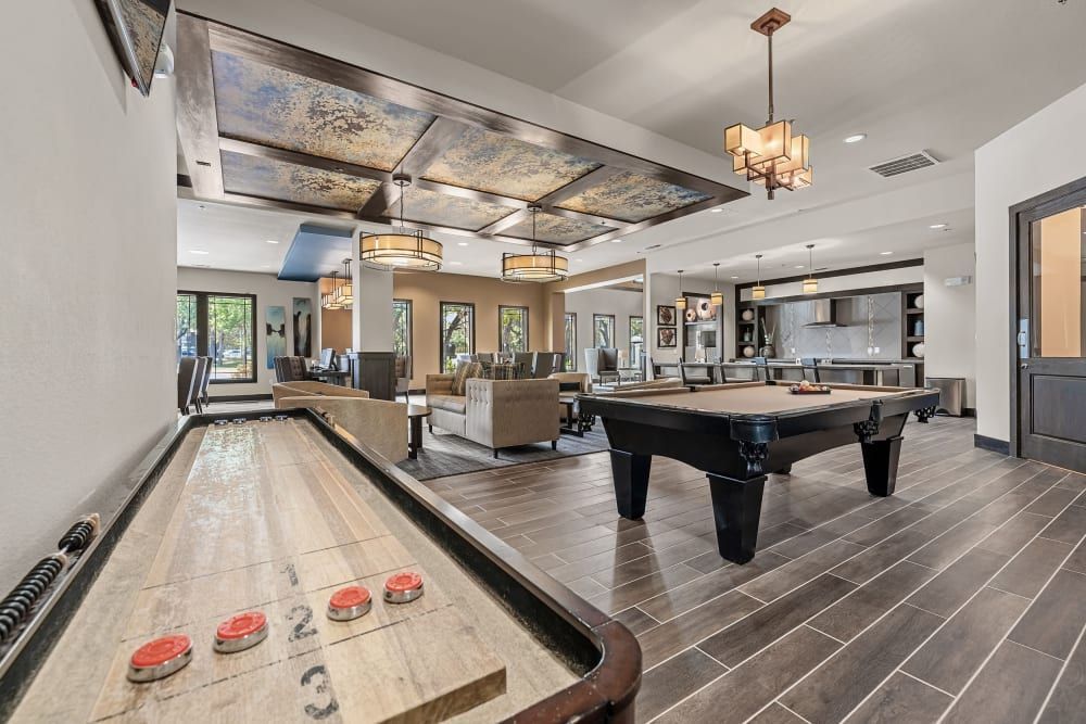a pool table and a shuffleboard table in the middle of the room at Marquis on Lakeline in Cedar Park, TX.