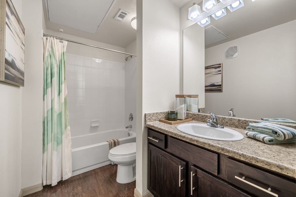 a bathroom with a sink, toilet, bathtub, and mirror at Marquis on Lakeline in Cedar Park, TX.