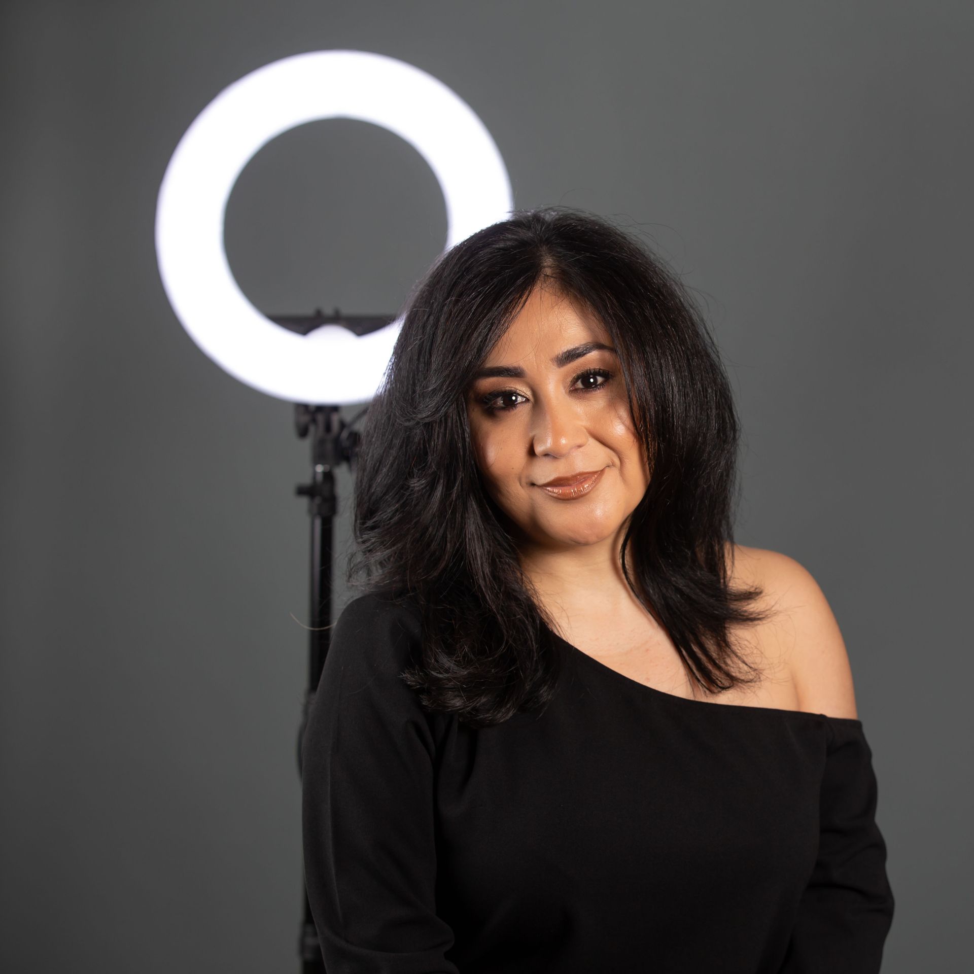 A woman is standing in front of a ring light.
