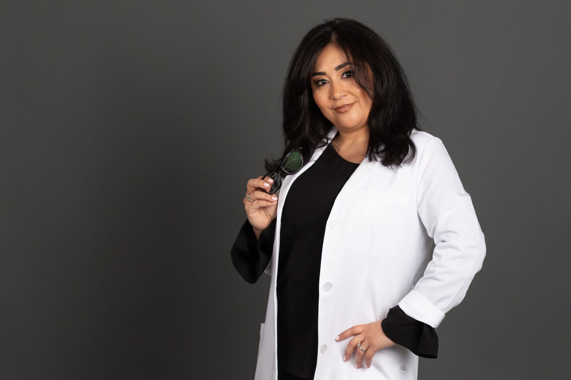 A woman in a white lab coat is holding a magnifying glass.