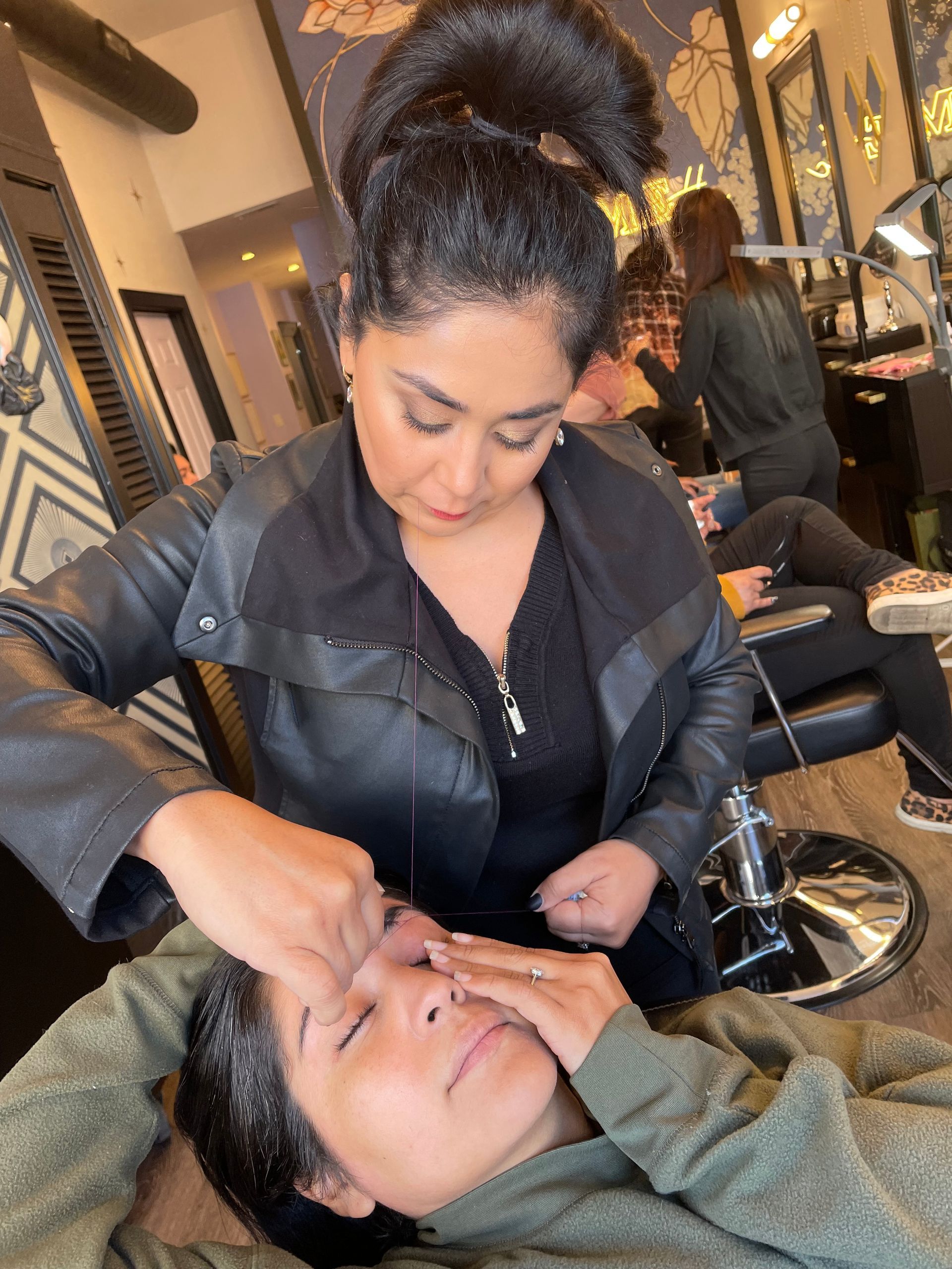 A woman is applying makeup to a woman 's face in a salon.