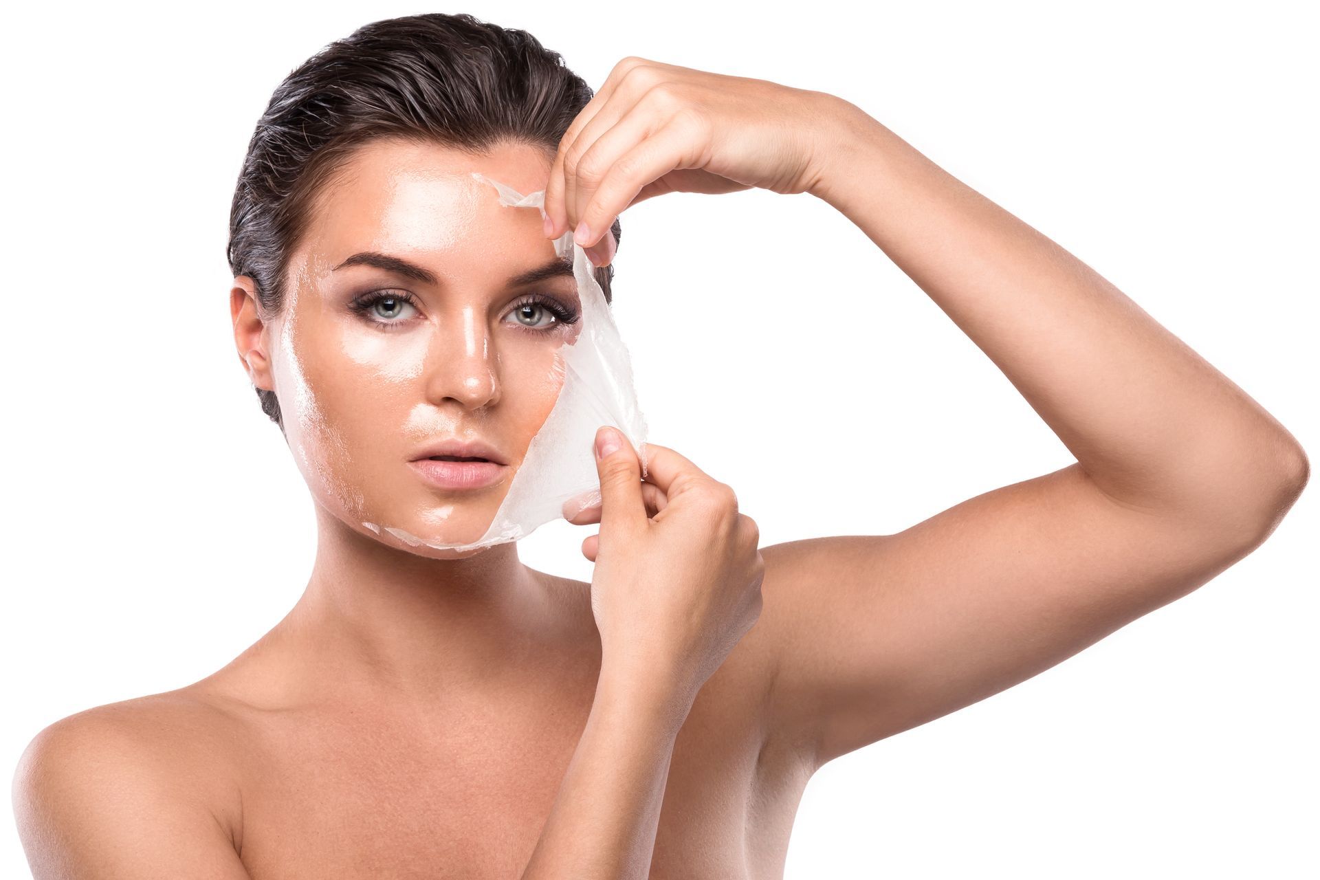 A woman is peeling off a sheet of paper from her face.