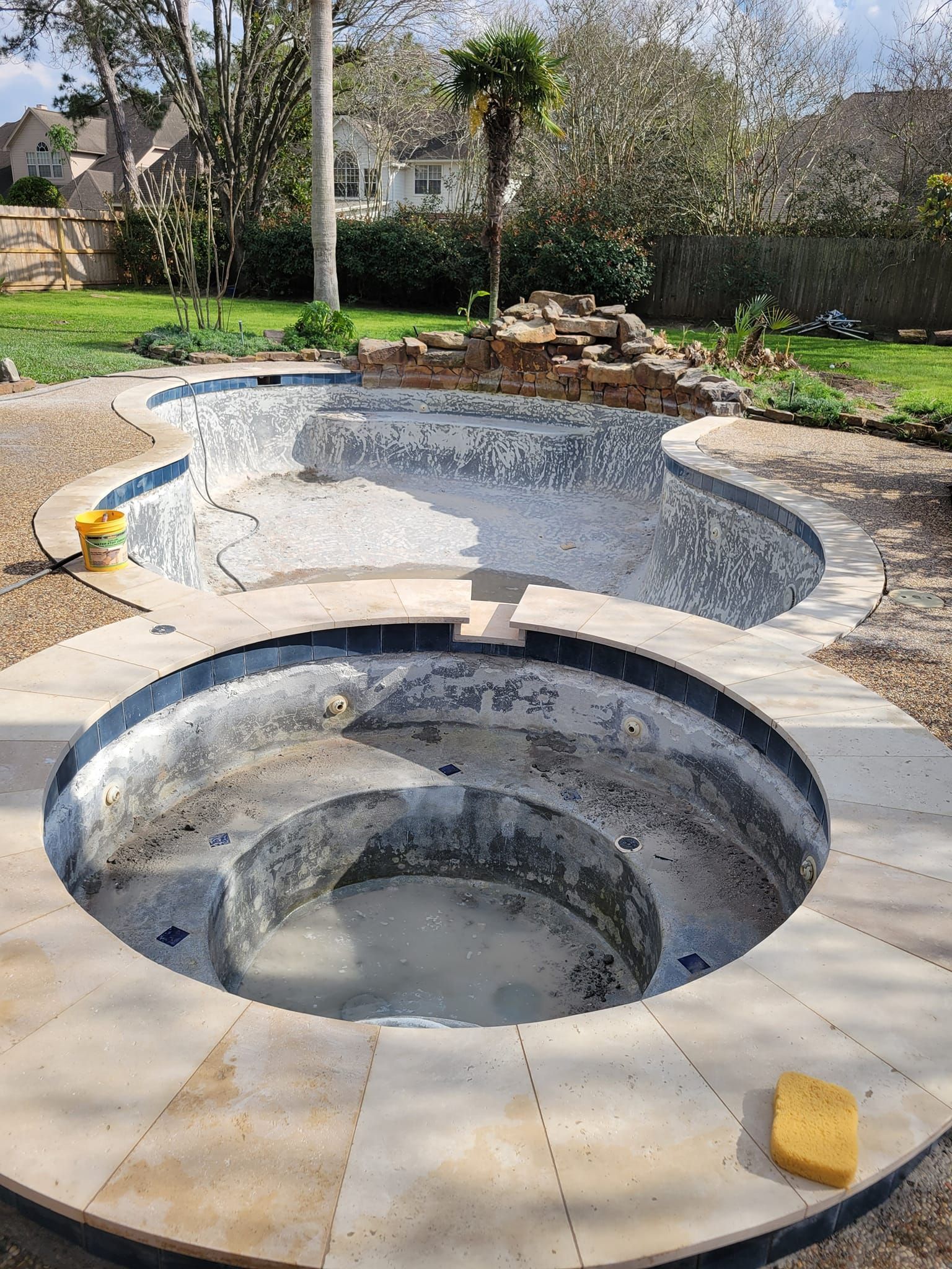 Empty outdoor backyard hot tub under construction, with a tiled pool and surrounding patio.