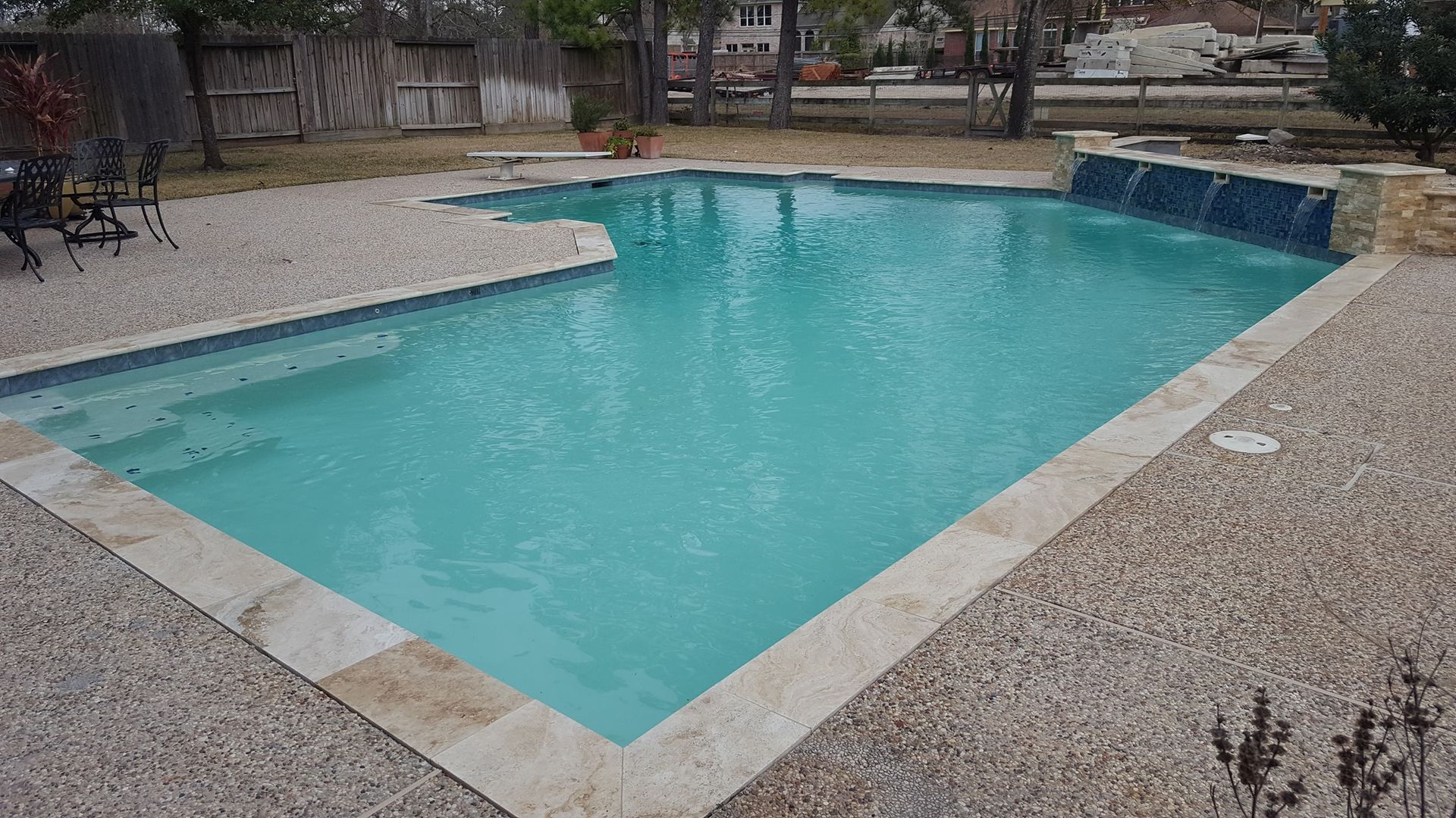 A large swimming pool with a waterfall in the backyard.