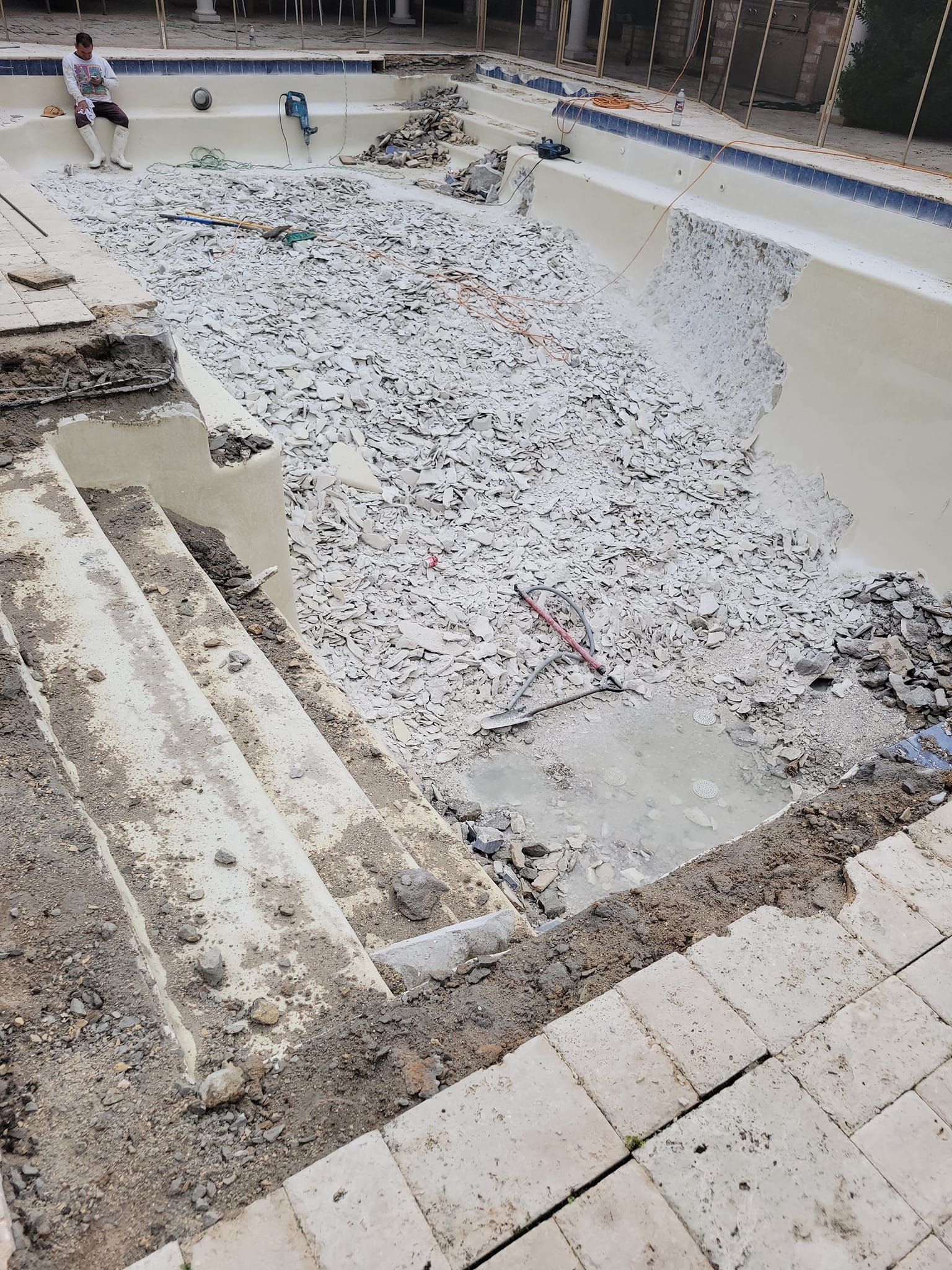 Workers in a drained pool clearing debris and mud from the basin