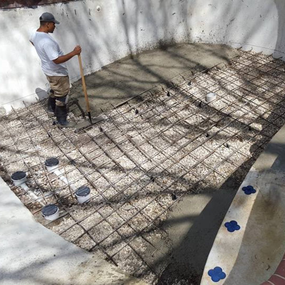 Worker leveling rebar mesh in a concrete foundation pit