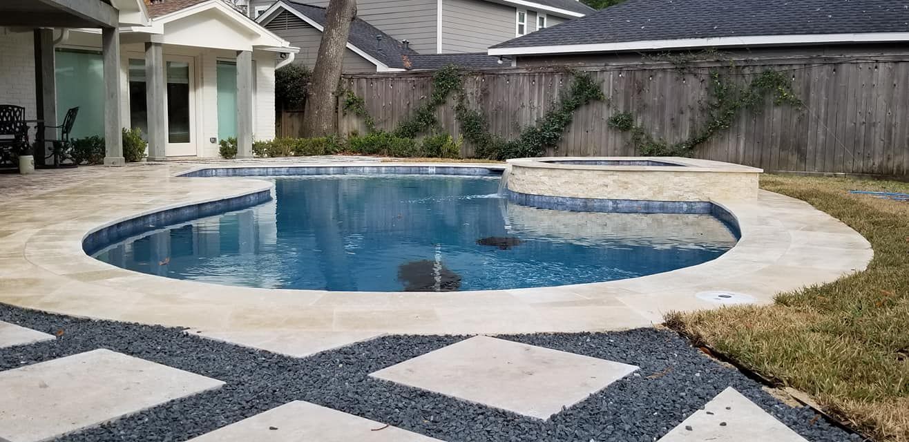 Backyard pool with a concrete deck and stone pavers beside a fenced yard