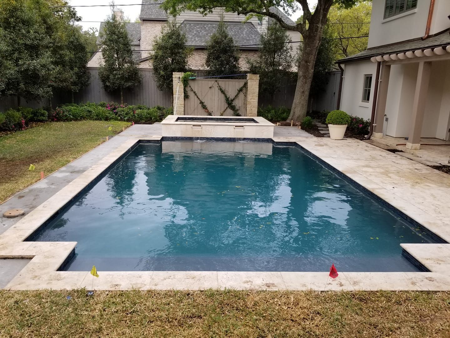 Rectangular backyard swimming pool with blue water, stone deck, and patio seating area.