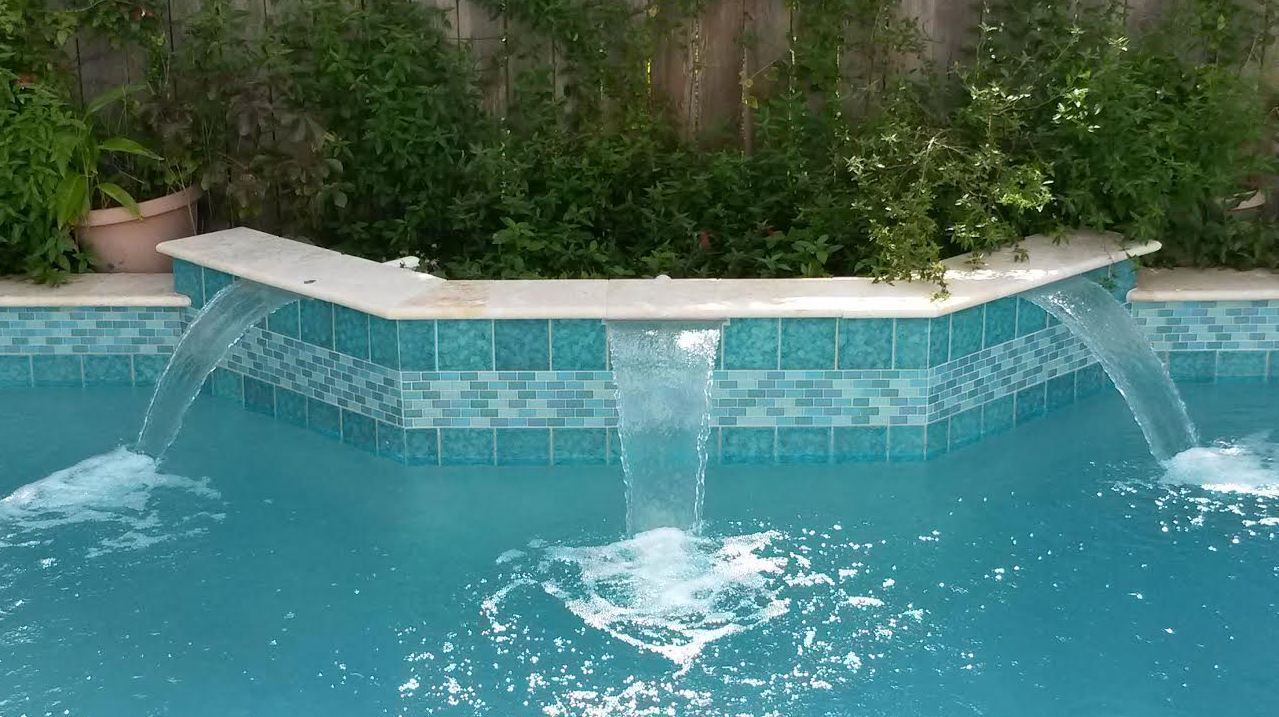 Swimming pool with turquoise water, blue tile wall, and two water spouts flowing into it