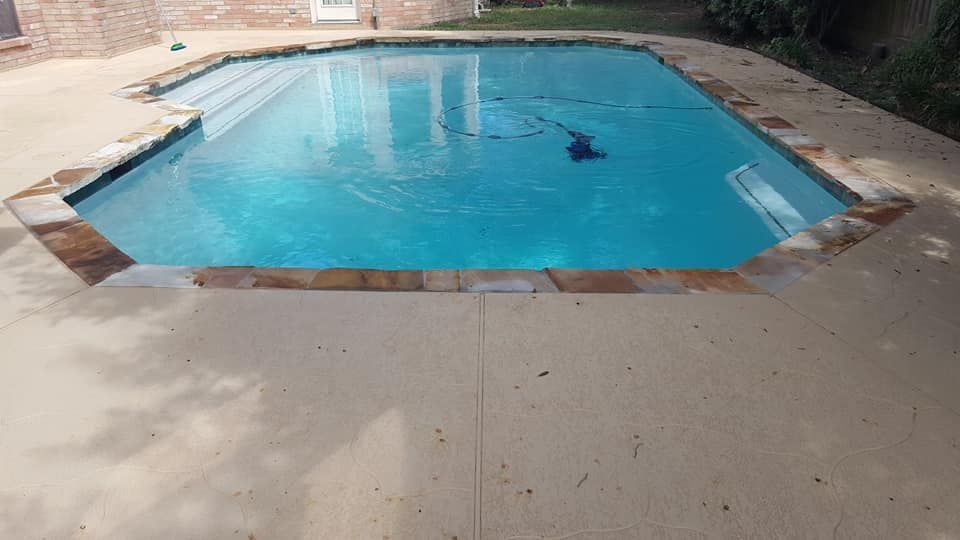Backyard swimming pool with clear blue water and concrete deck around it