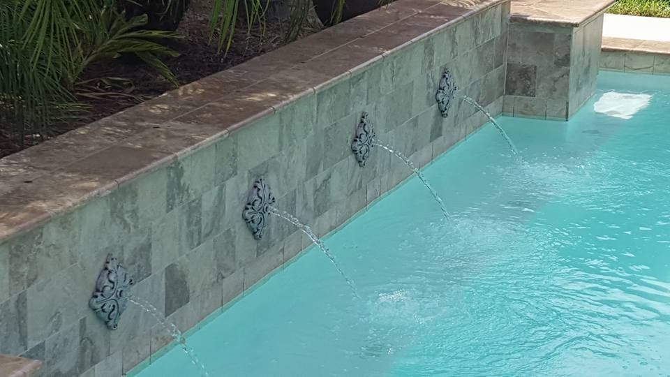 Turquoise pool with a tiled retaining wall and water feature spillway