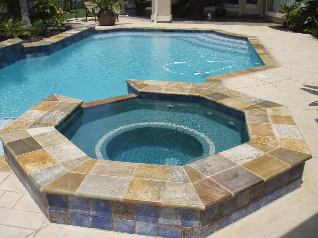 Backyard pool with a raised hexagonal hot tub in tan stone and blue water
