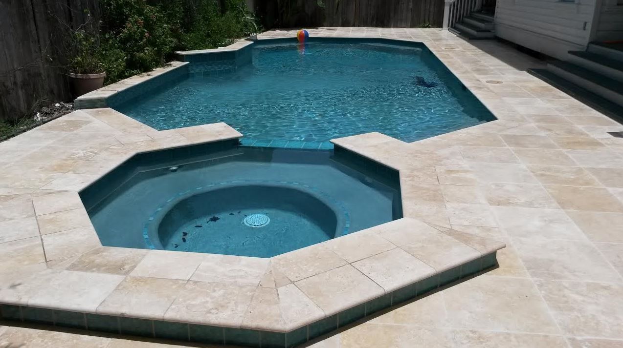 Backyard swimming pool with attached raised spa and stone patio surroundings