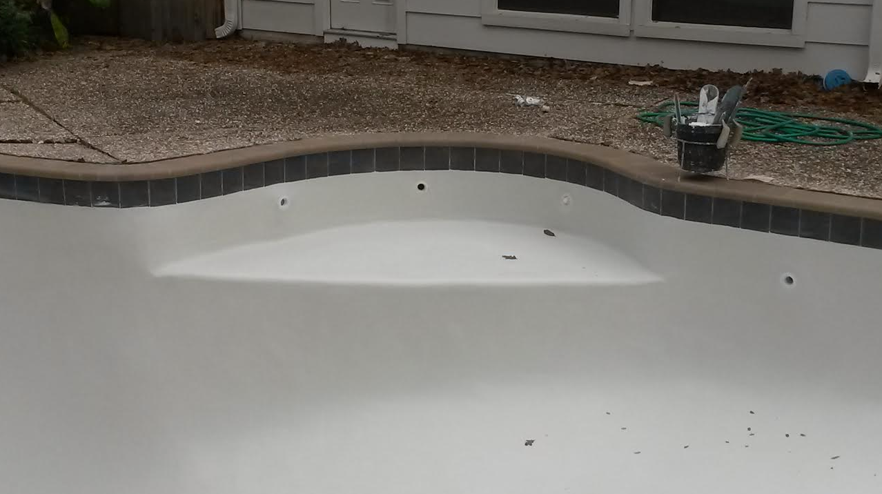 Backyard pool with a large patch of white foam covering the water surface