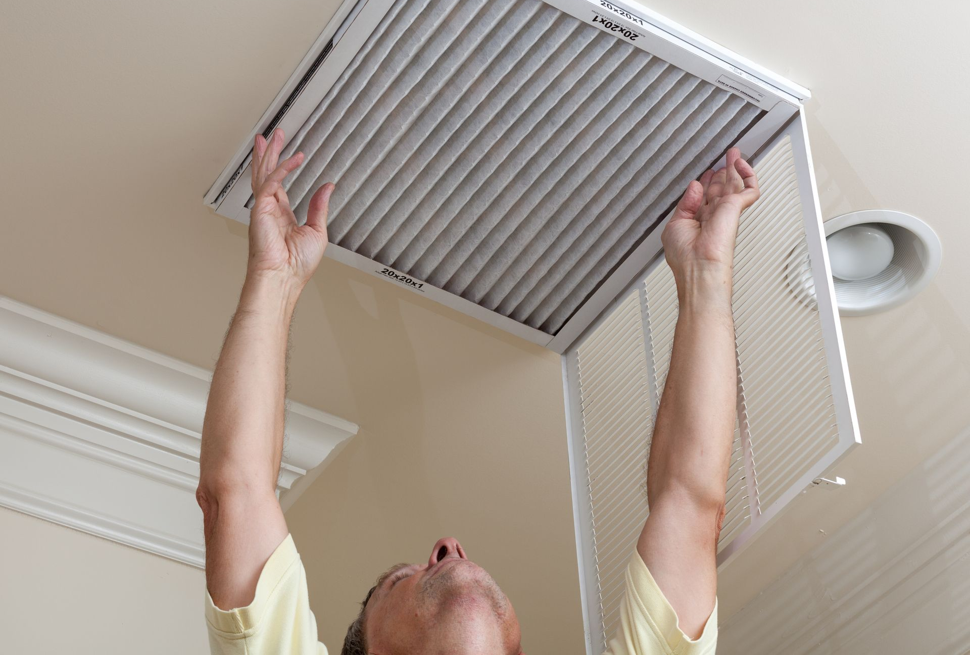 Man opening ceiling air conditioning filter for home duct air care. Man opening ceiling air conditioning filter for home duct air care.