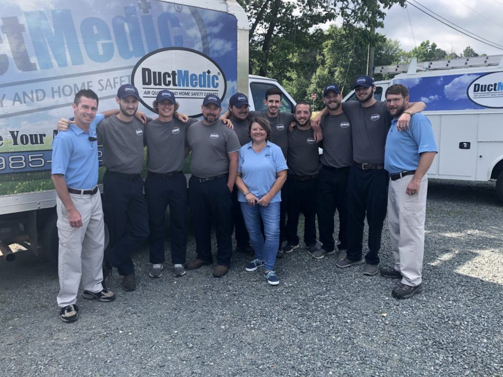 A group of people posing for a picture in front of a truck that says ductmedic