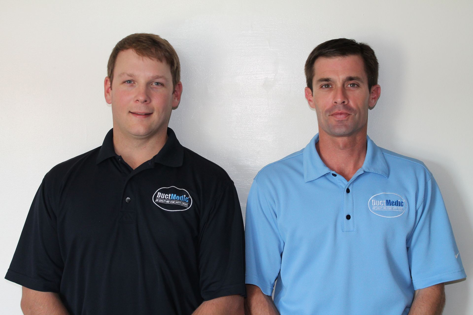 Two men standing next to each other wearing blue shirts