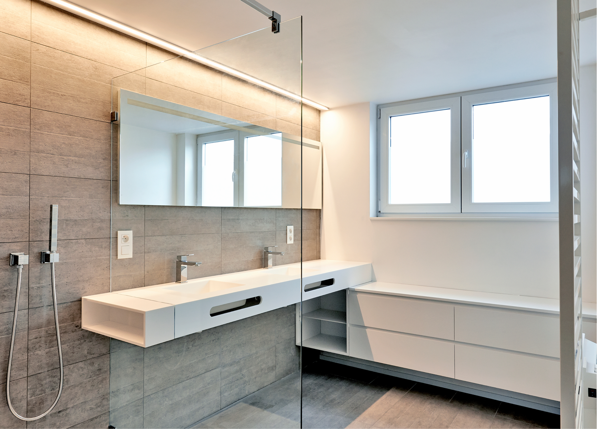 A modern gorgeous bathroom with two sinks and a walk-in shower and large glass door remodeled by Ace Siding Windows and Roofing. 