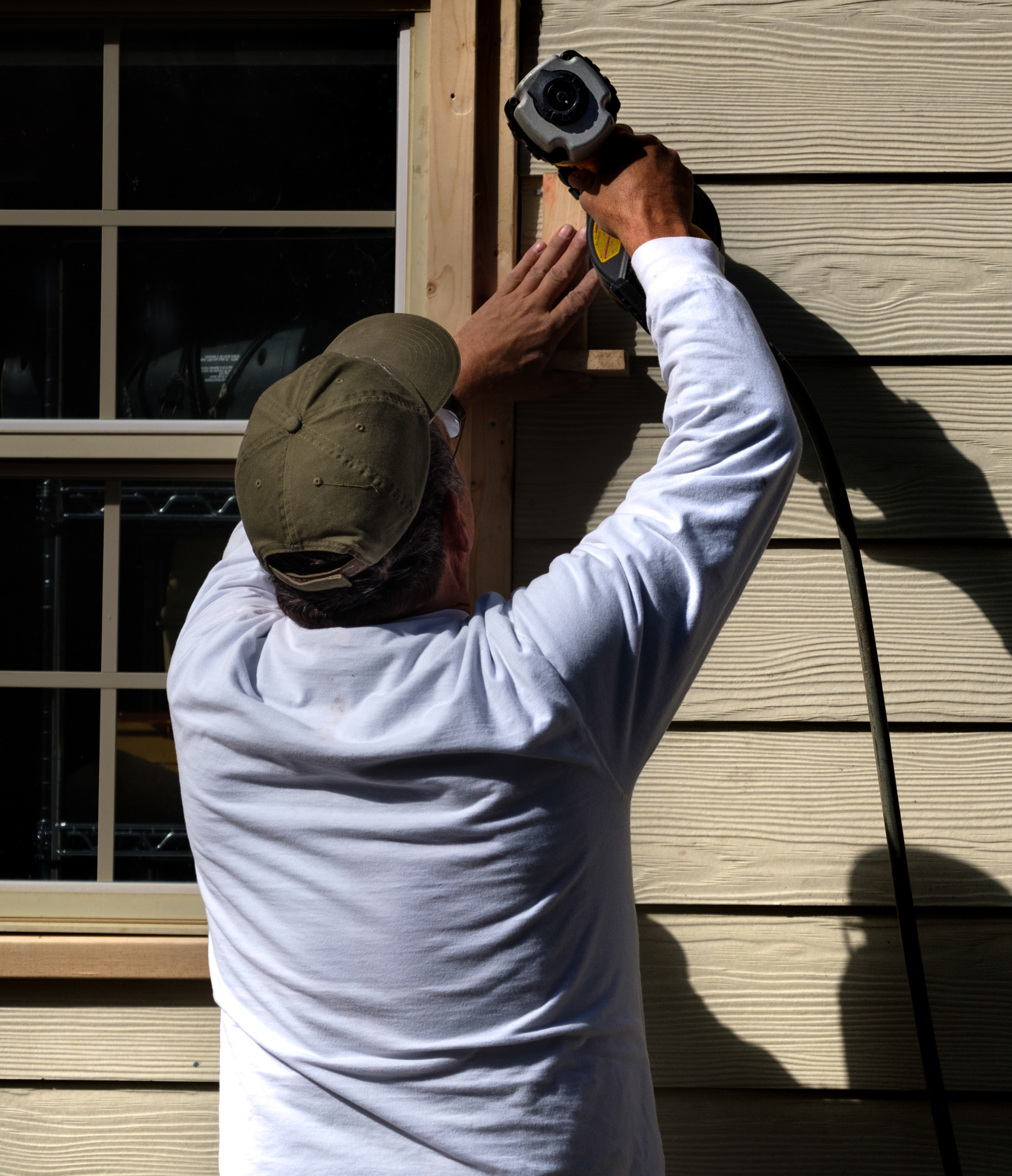 A man is working on a window frame with a drill