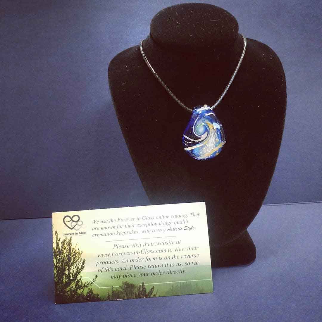 A necklace with a blue pendant is on a mannequin