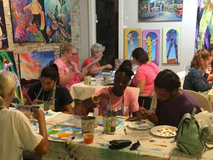 A group of people are sitting around a table painting.
