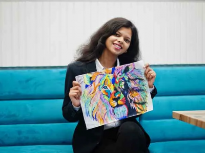 A woman is sitting on a couch holding a painting of a lion.