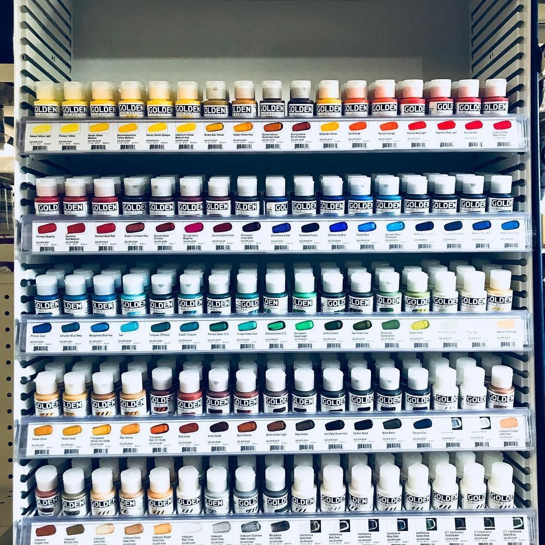 A shelf filled with lots of bottles of acrylic paint.
