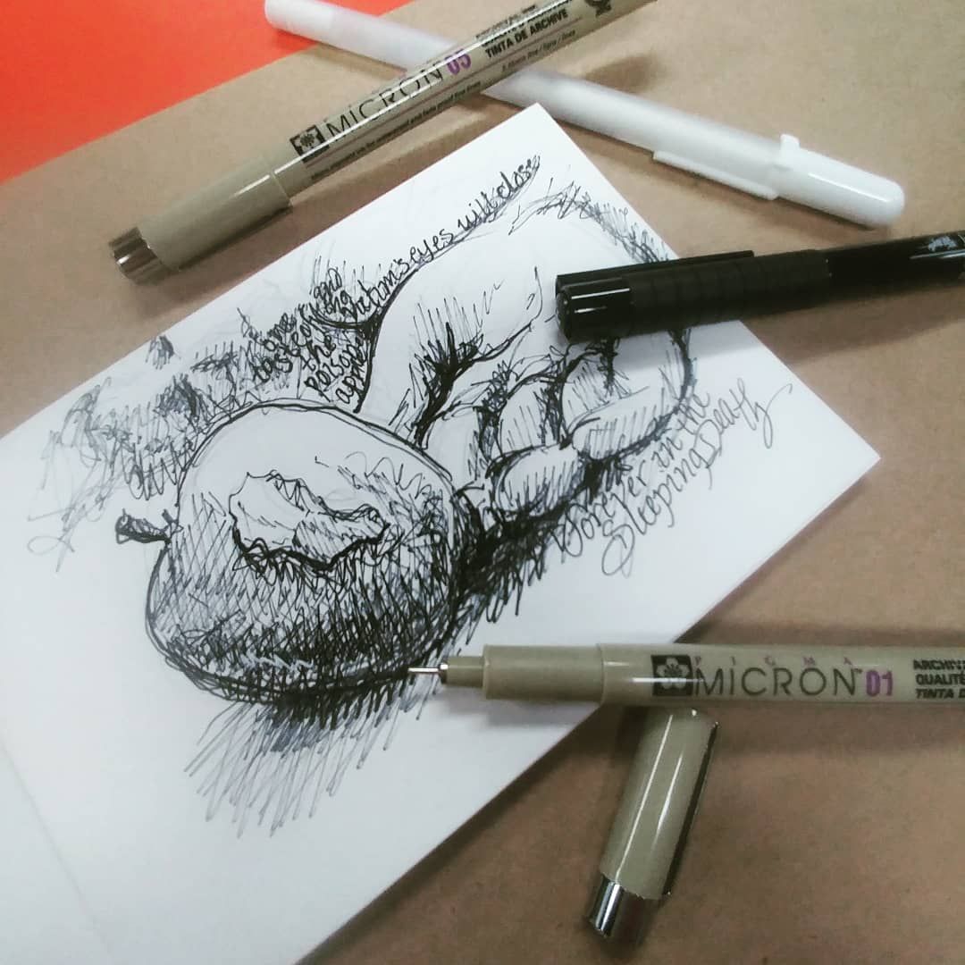 A drawing of an apple is on a piece of paper next to a micron pen