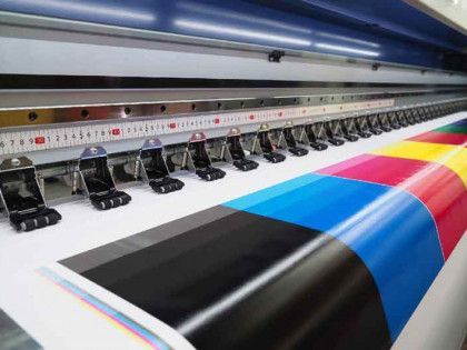 A large printer is printing a colorful sheet of paper.