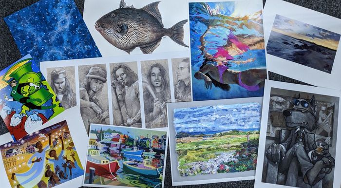 A bunch of paintings and drawings are sitting on a table.