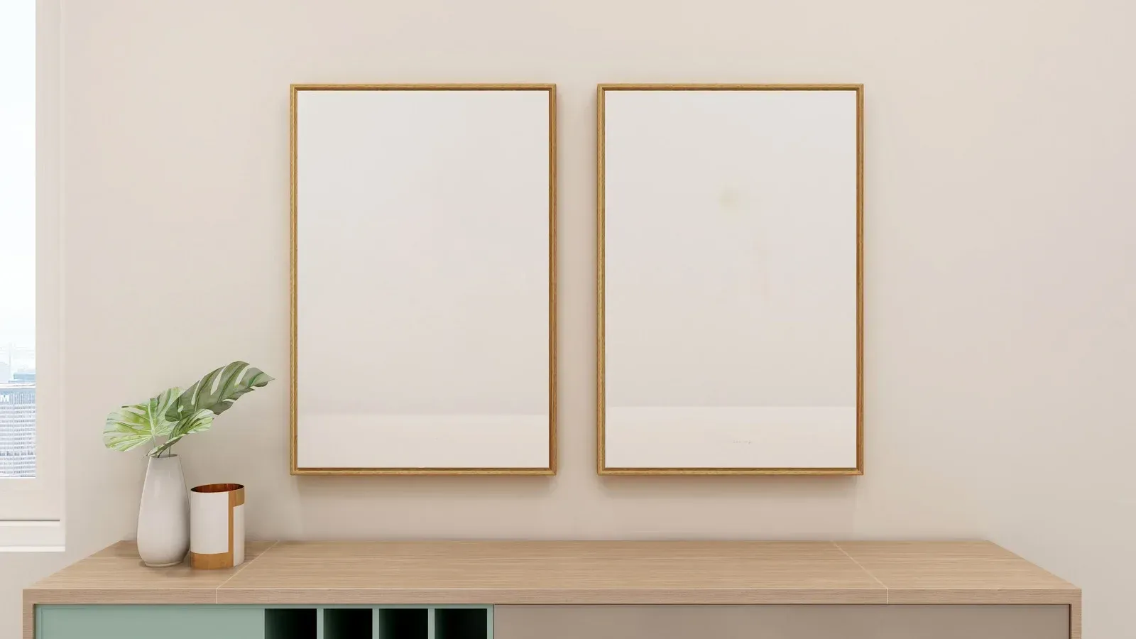 Two blank framed artworks above a wooden cabinet with a vase and decorative objects.