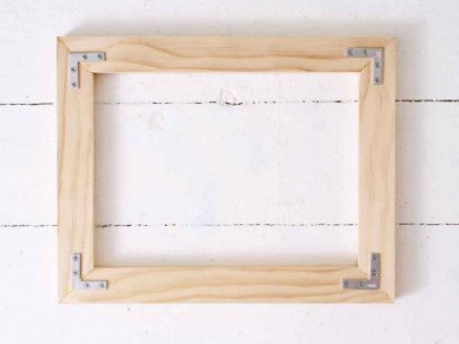 A wooden picture frame is hanging on a white wall.