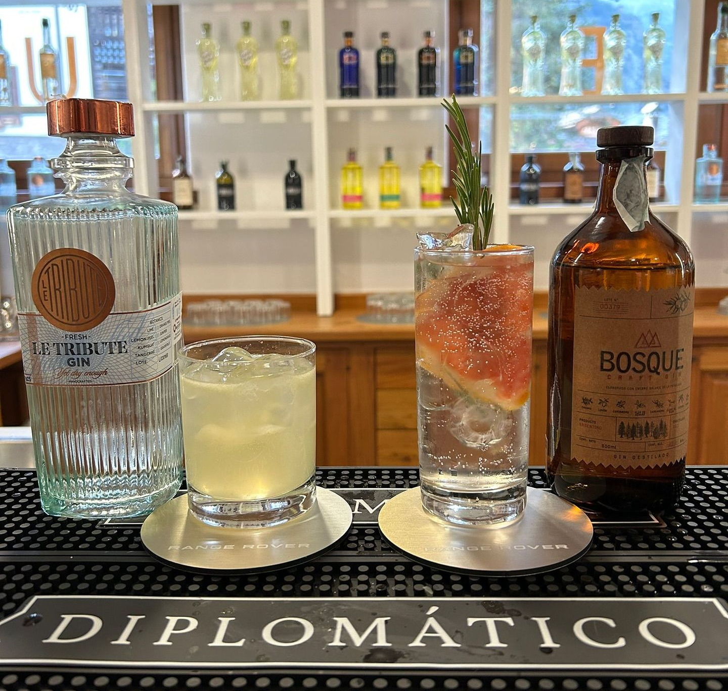 Una bottiglia di rum e tre cocktail su un tappetino da bar Diplomatico in un negozio di liquori.