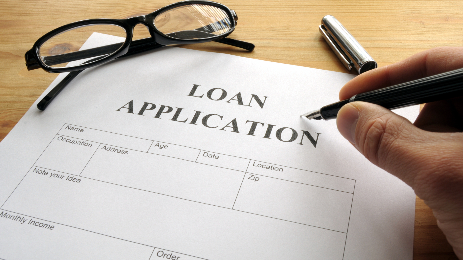 Loan application form with glasses and pen on a desk