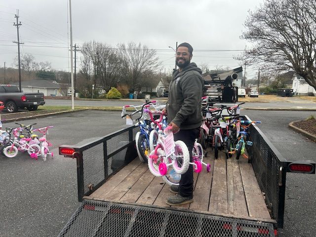 Man standing on trailer loaded with pink and white bicycles in a parking lot