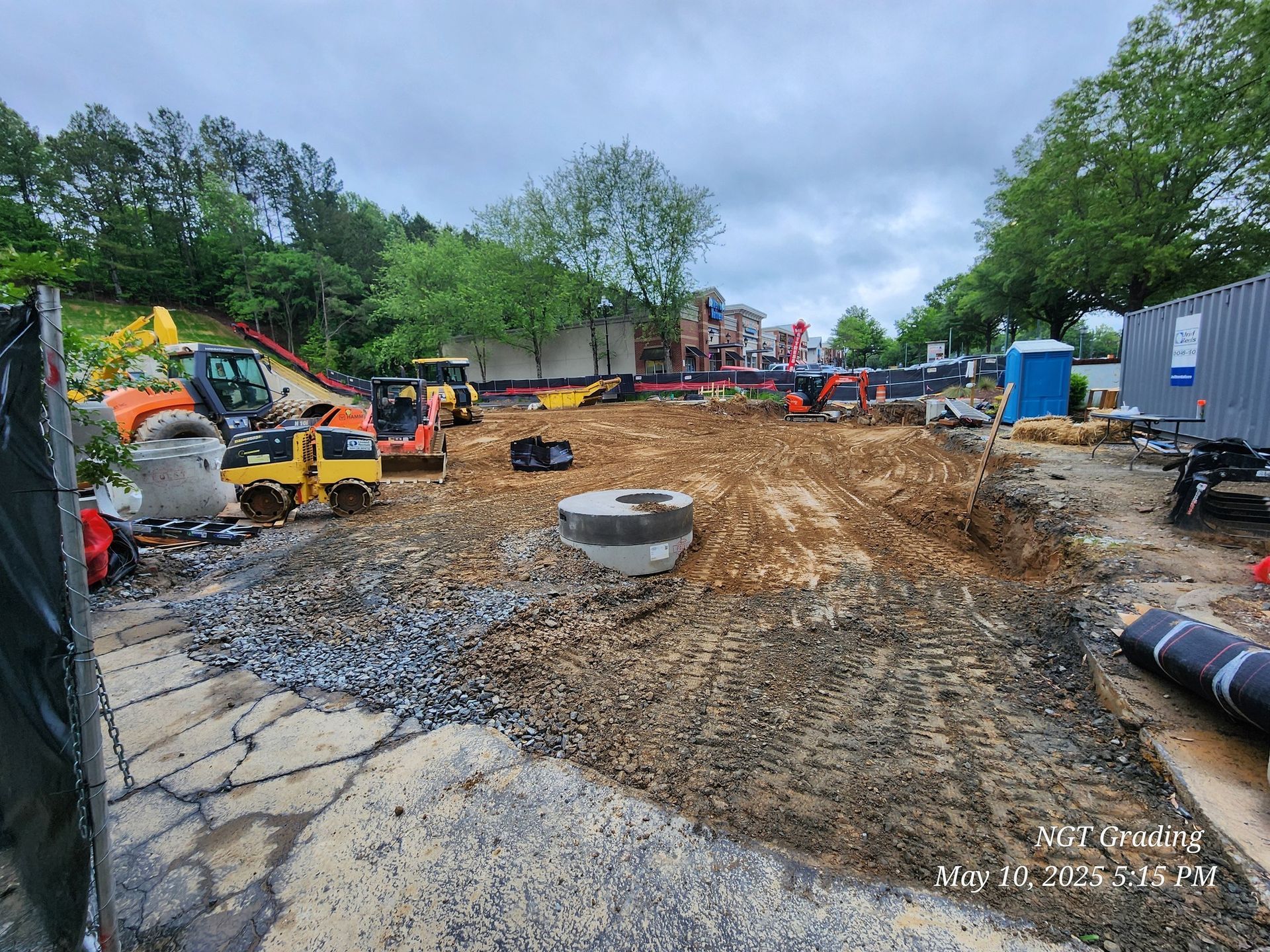 Construction site with excavators and trenching work on a muddy, excavated lot
