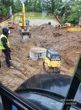 Construction site with excavators and workers digging a muddy trench