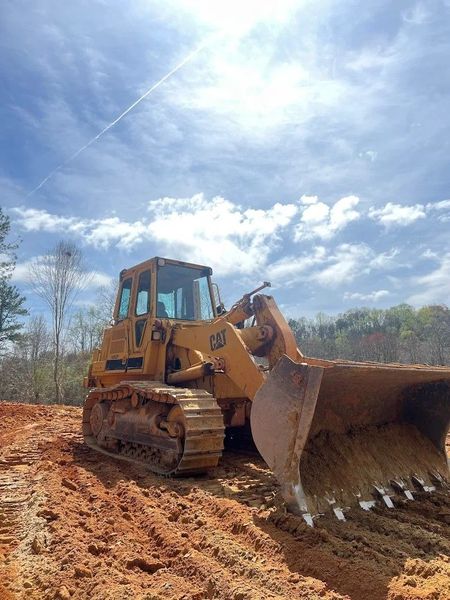 Yellow bulldozer on muddy ground under a bright cloudy sky