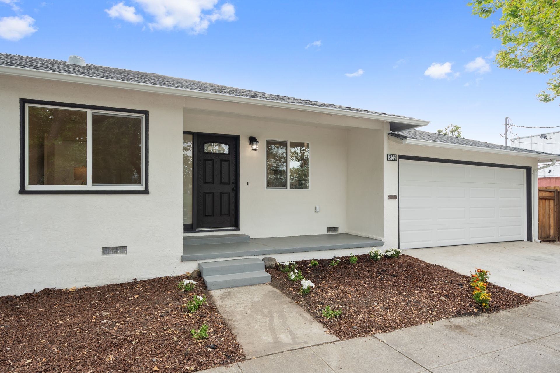 A white house with a black door and garage