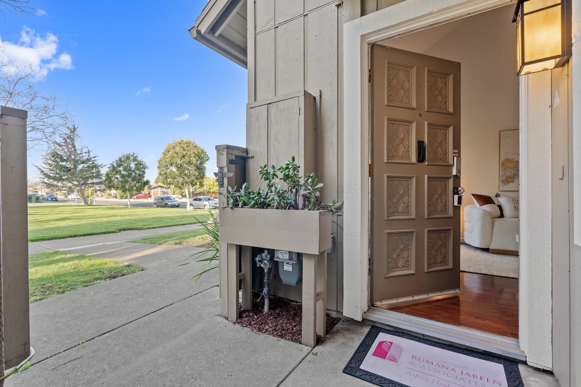 The front door of a house is open to a living room.
