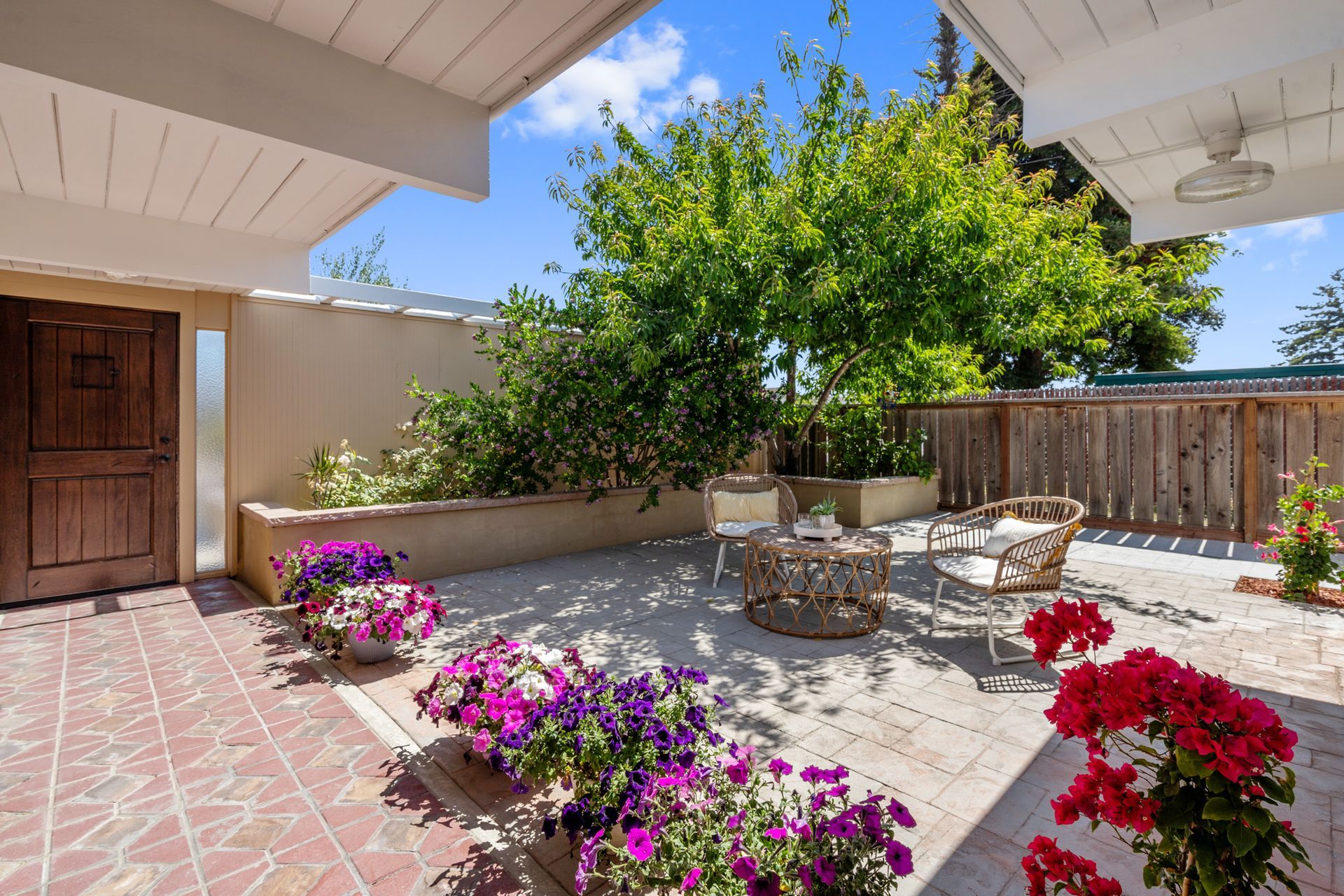 A patio with purple flowers and a table and chairs