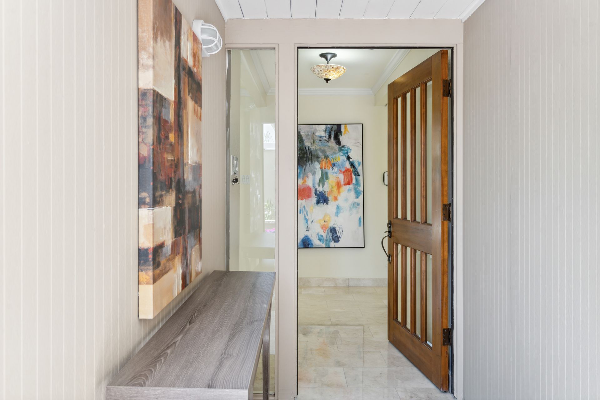 A hallway with a wooden door and a painting on the wall.
