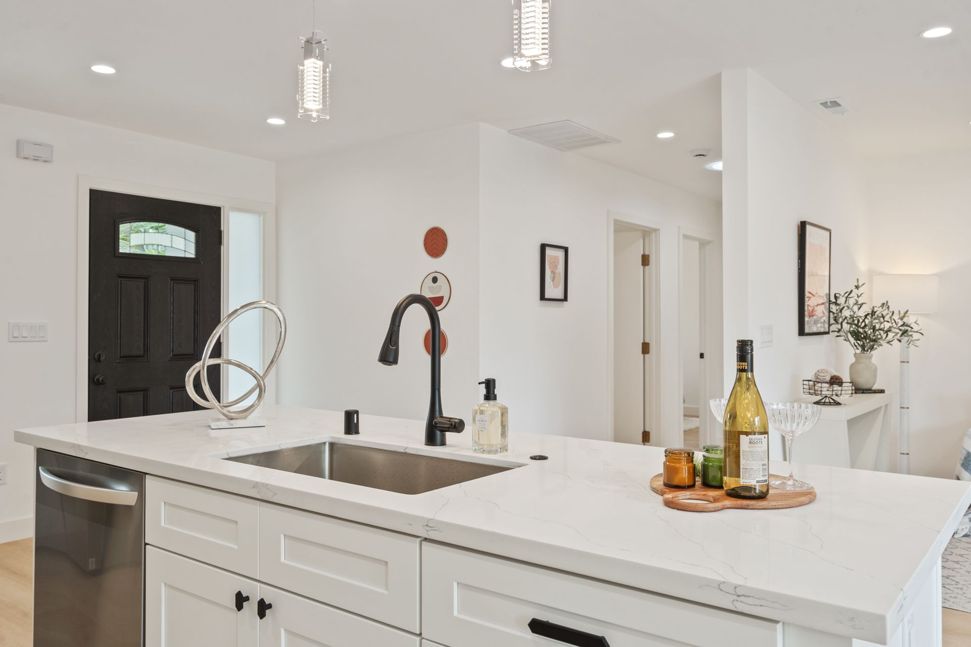 A kitchen with a sink and a bottle of wine on the counter.