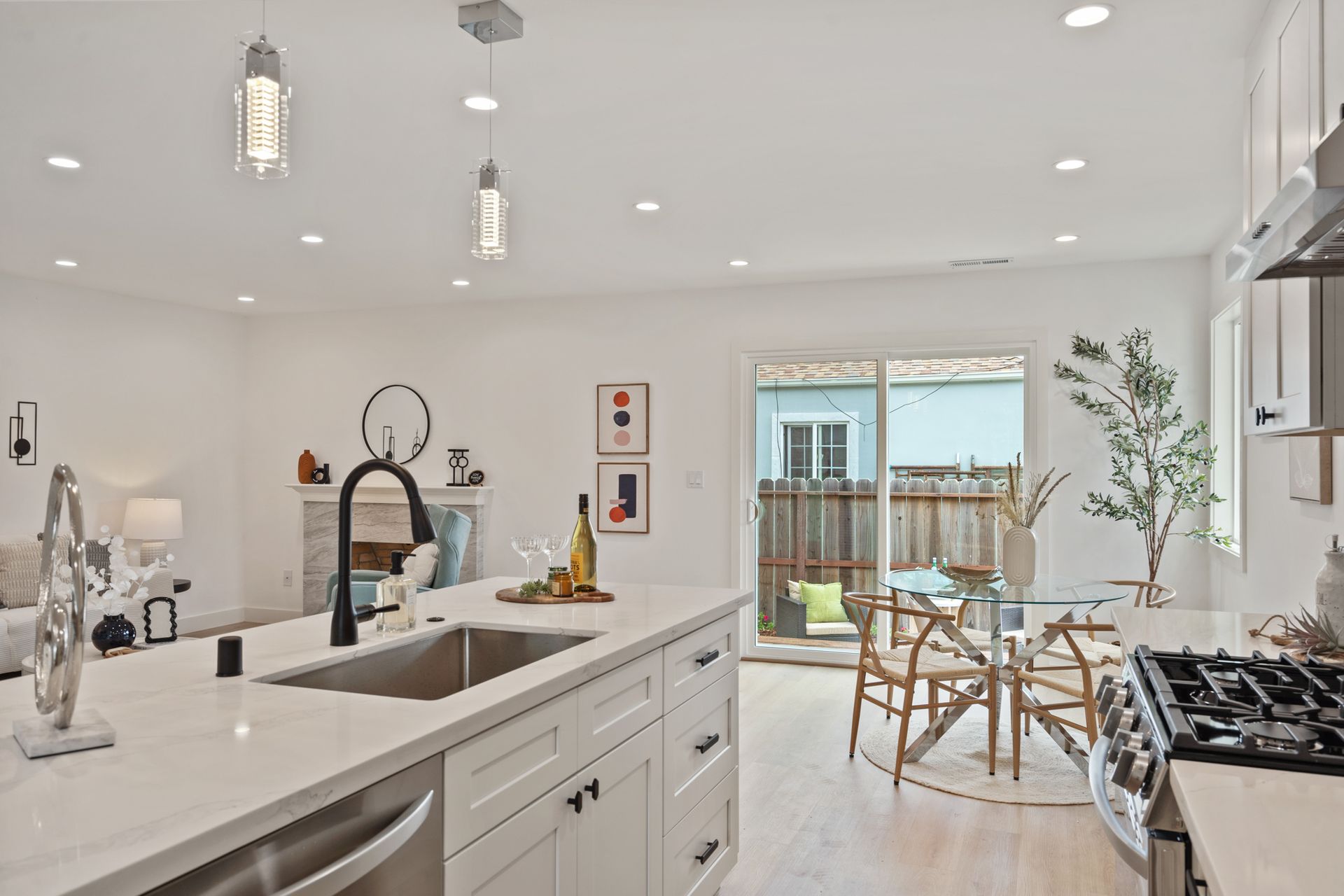 A kitchen with a sink , stove , dishwasher and sliding glass doors leading to a dining room.