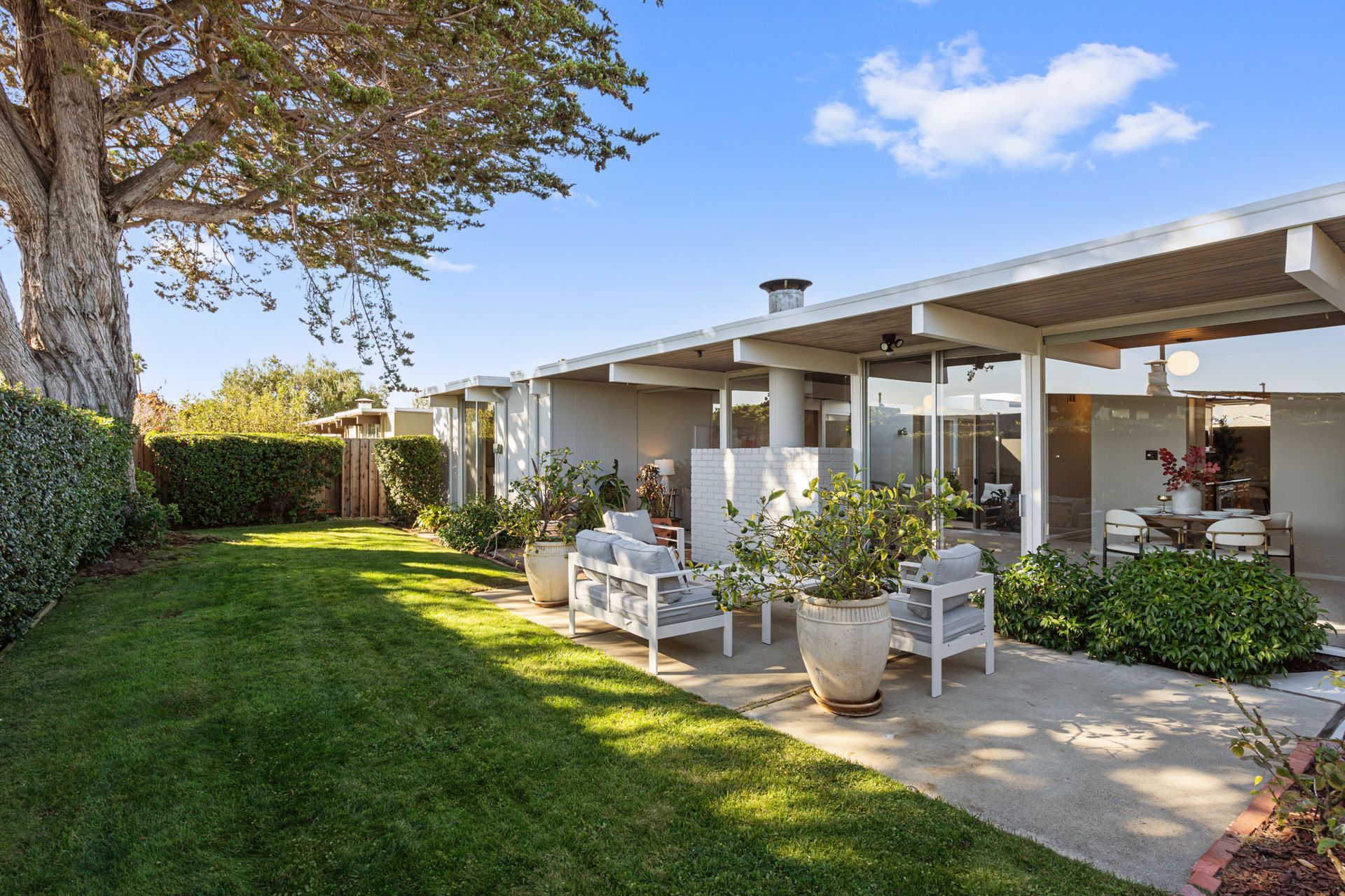 A house with a large lawn and patio area in front of it.
