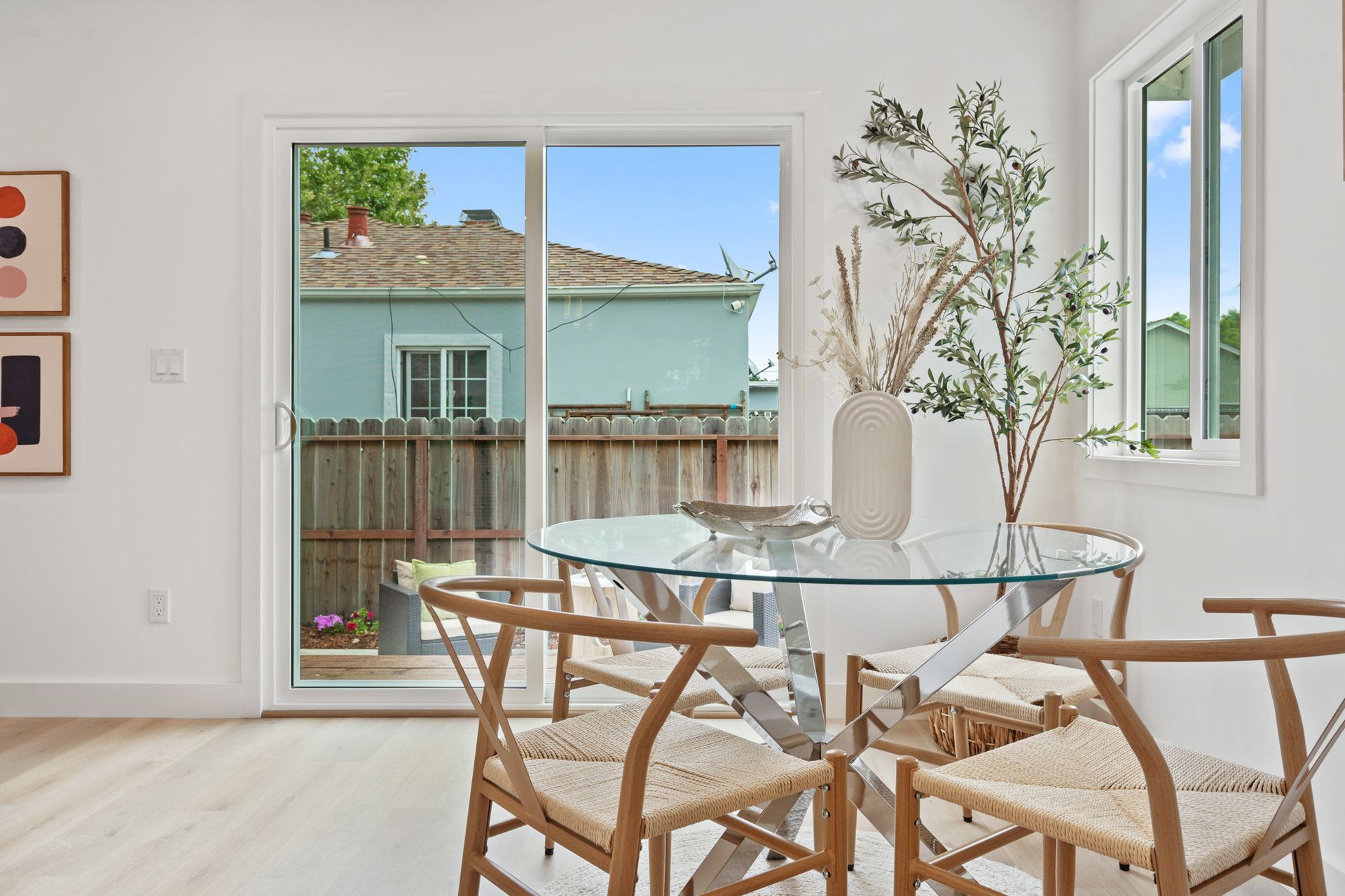 A dining room with a glass table and chairs and a sliding glass door.