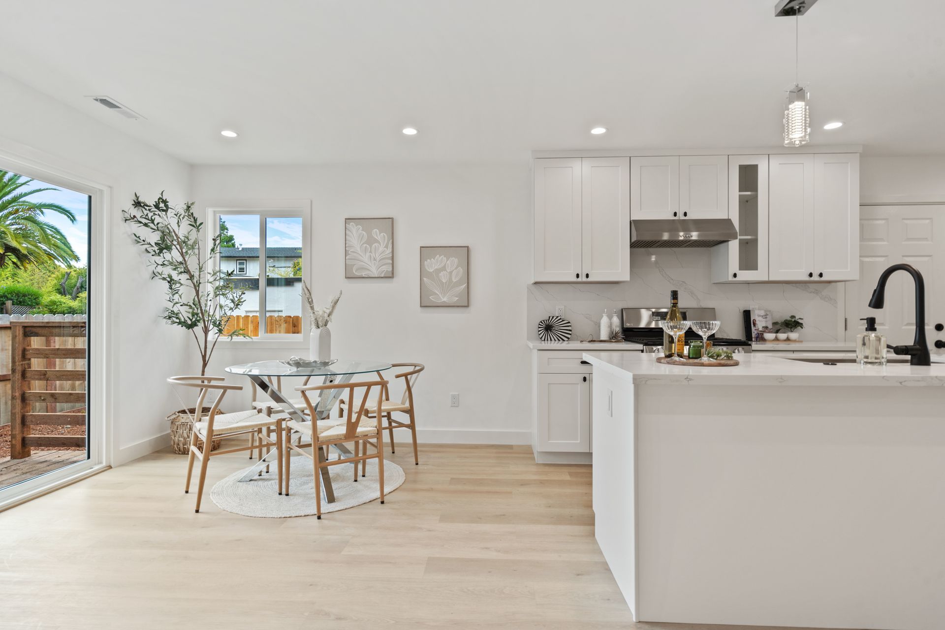 A kitchen with white cabinets and a dining room with a table and chairs.