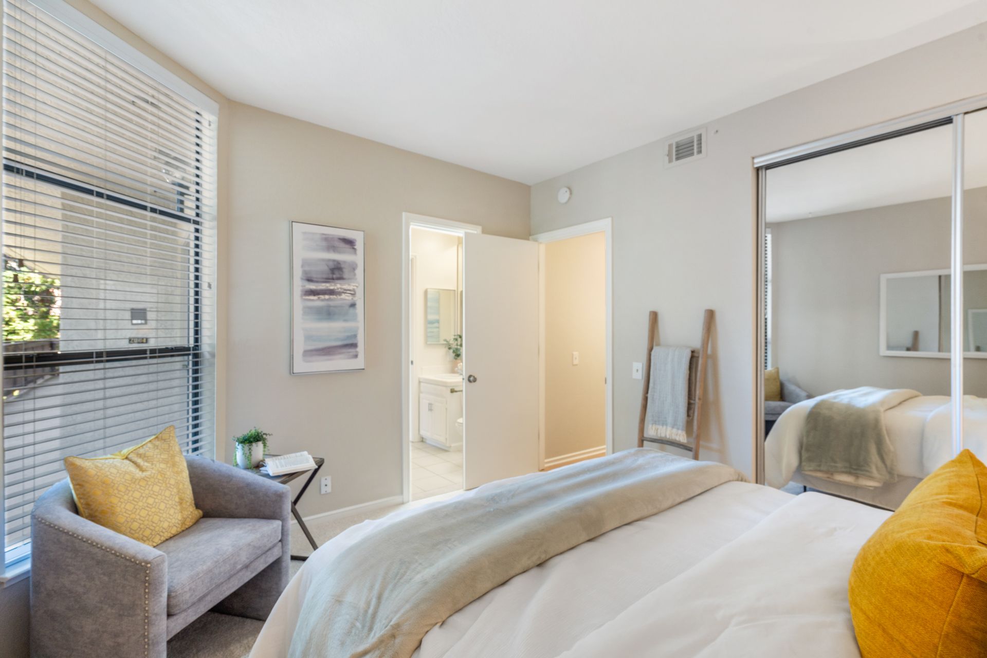 A bedroom with a bed , chair , table and mirror.