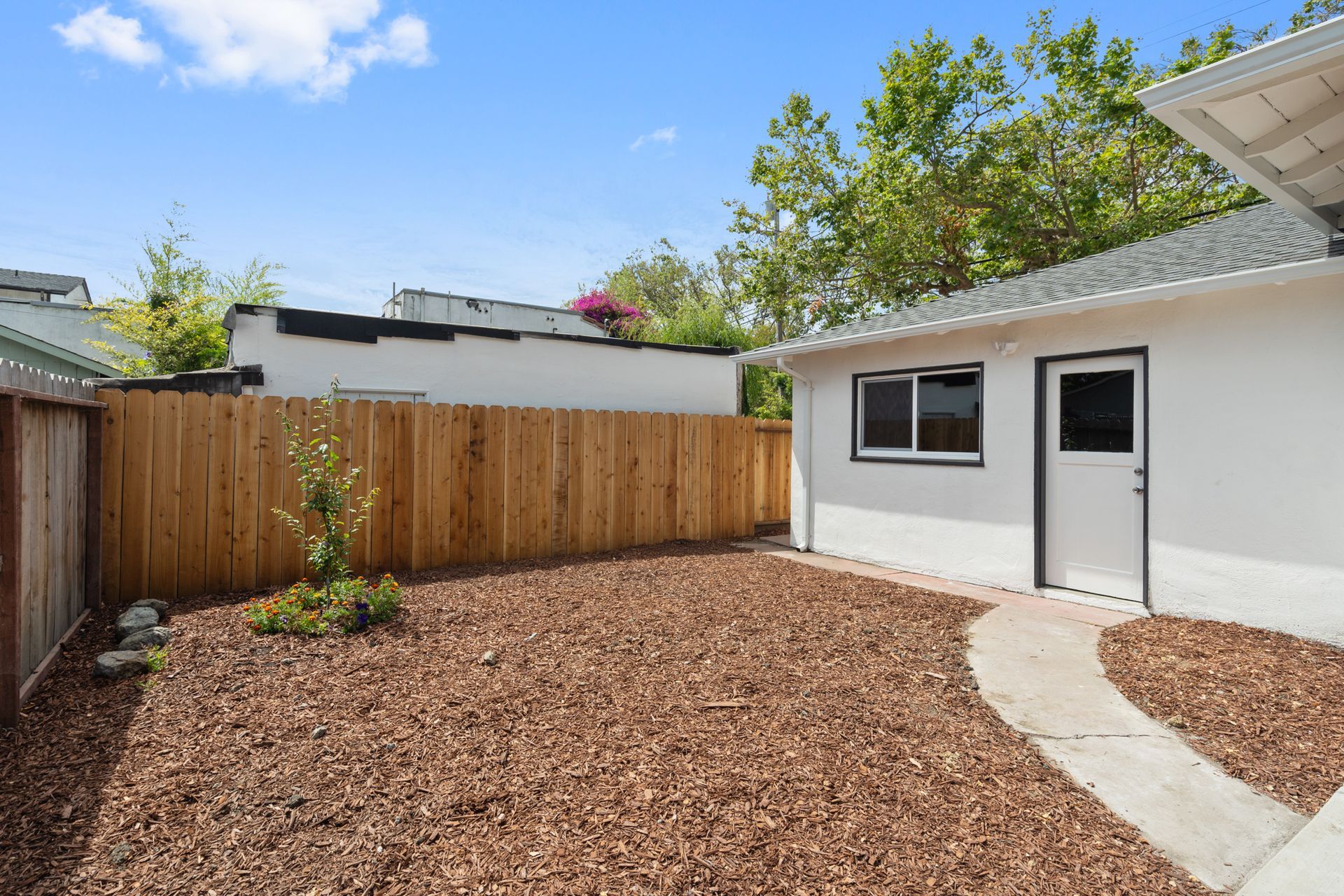 A white house with a wooden fence in the backyard