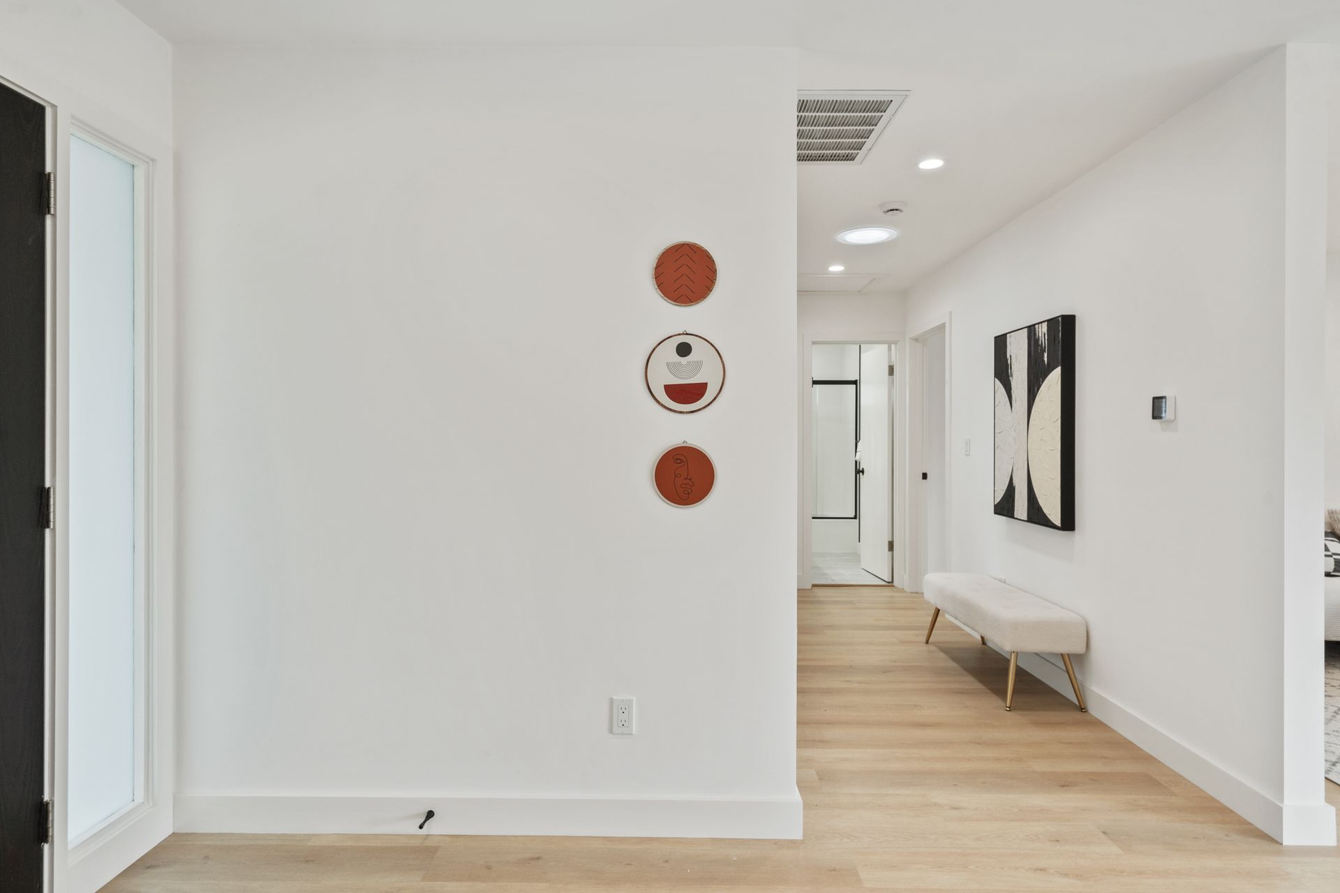 A hallway with a bench and a painting on the wall.